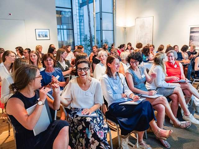 Large group of smiling women sitting in an audience